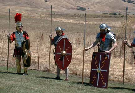 Gaius Germanicus Magnus (Steve Oster), Patti Ballard, and Antony Lucius (Anthony Garbisch) stand with pilum and shield ready.